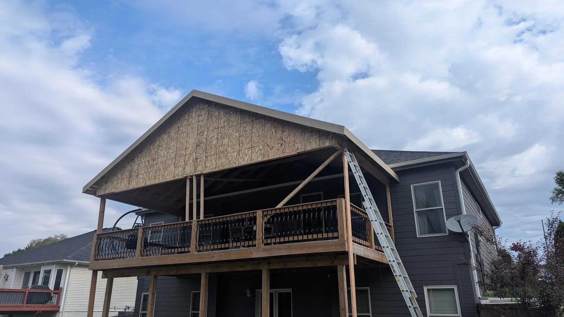 Second-story covered deck under construction with gable roof framing