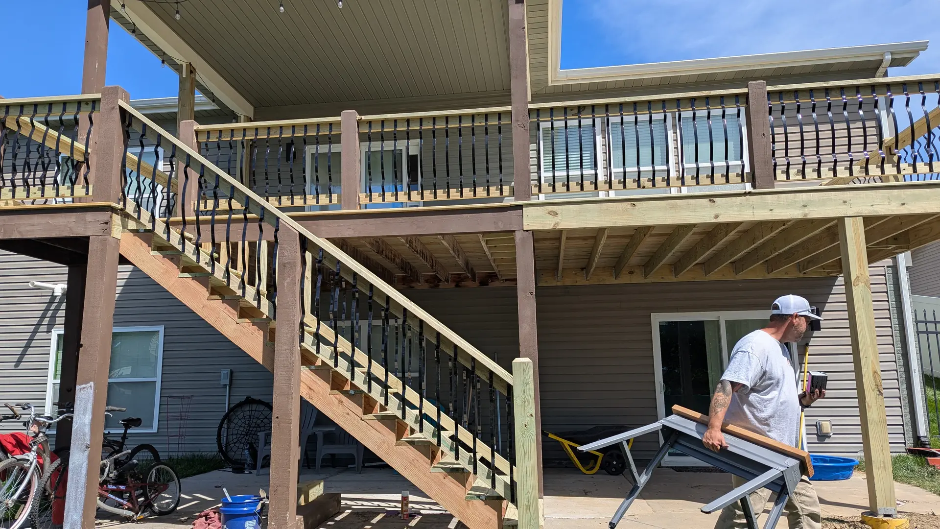 Elevated deck stairs with black metal railing and decorative balusters