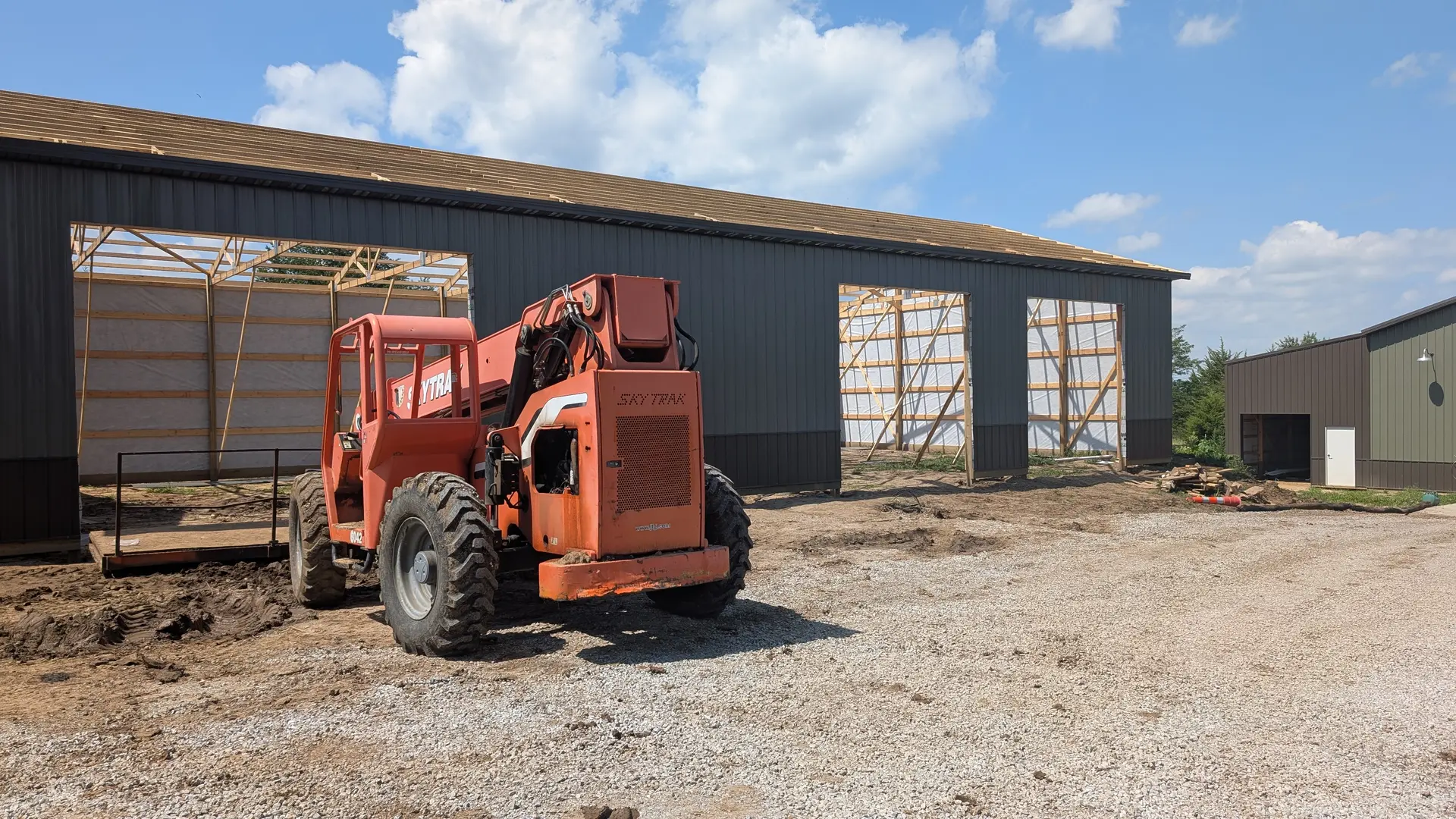 Steel pole barn under construction with a telehandler on a rural site
