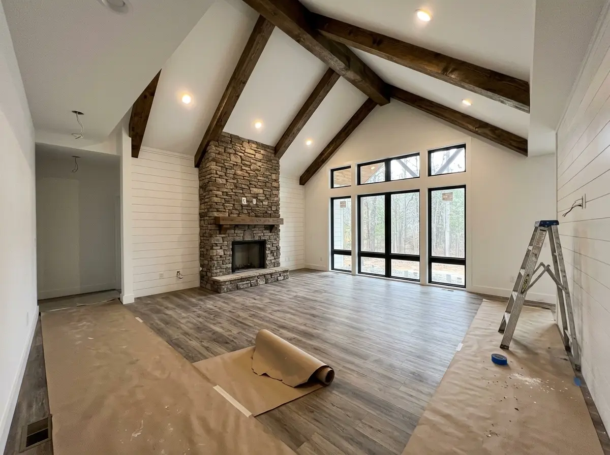 The vaulted great room of a finished custom home with stained beams and a stone fireplace